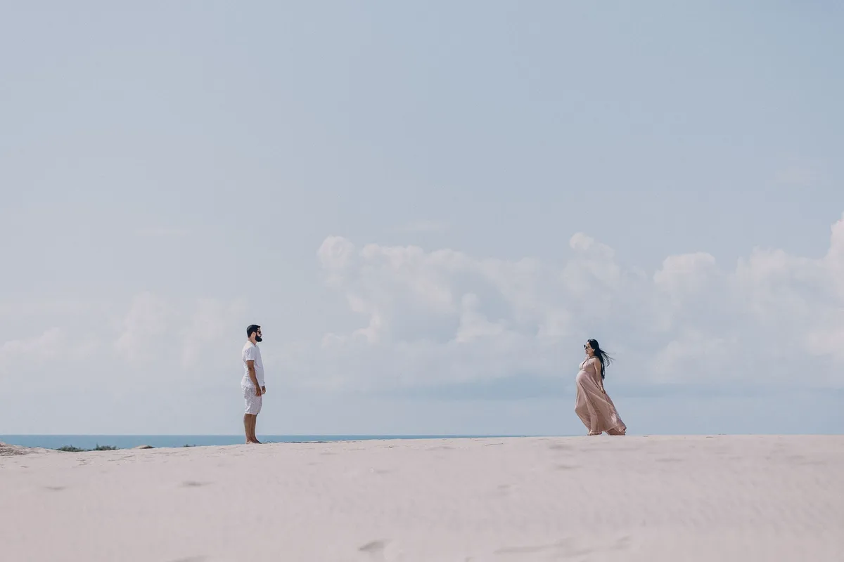 A man and a woman standing far apart on an empty stretch of sand