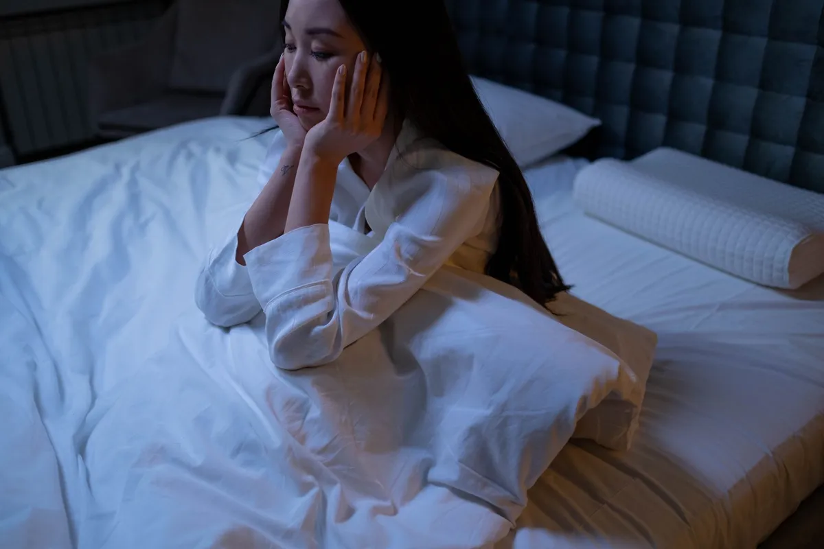 A woman lying awake at night, a common betrayal trauma symptom