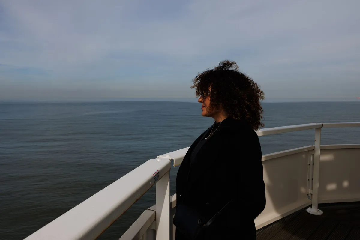 A woman standing outdoors looking toward the horizon