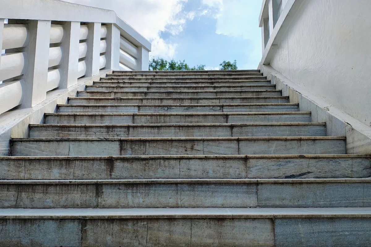 A wide flight of concrete steps seen from below, leading up towards the sky