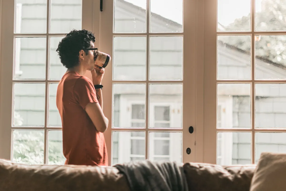 A man sitting alone by a window, doing the work of a marriage break up on his own