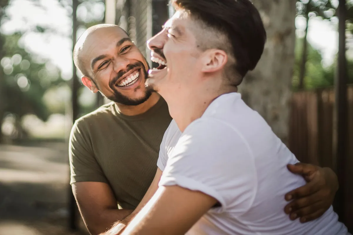 A couple laughing together outdoors in sunlight