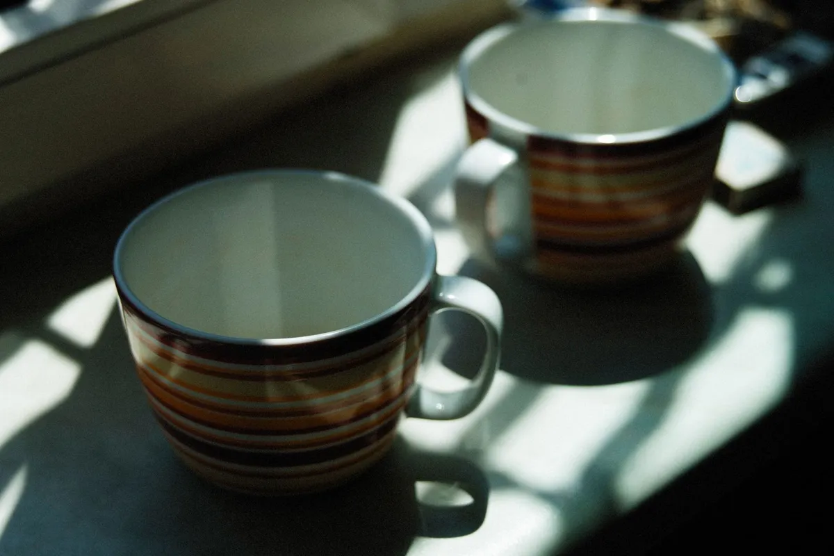 Two coffee cups on a kitchen counter in morning light, the small daily bids that reconnect a marriage