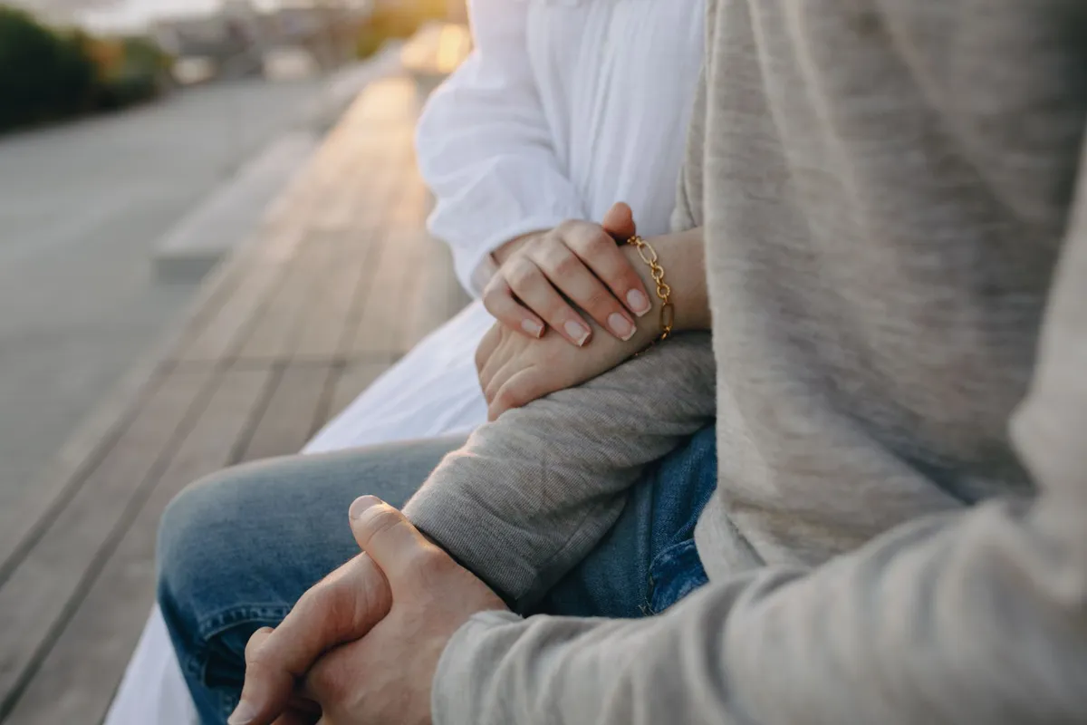 Two people holding hands quietly, the ordinary contact that goes first in a marriage