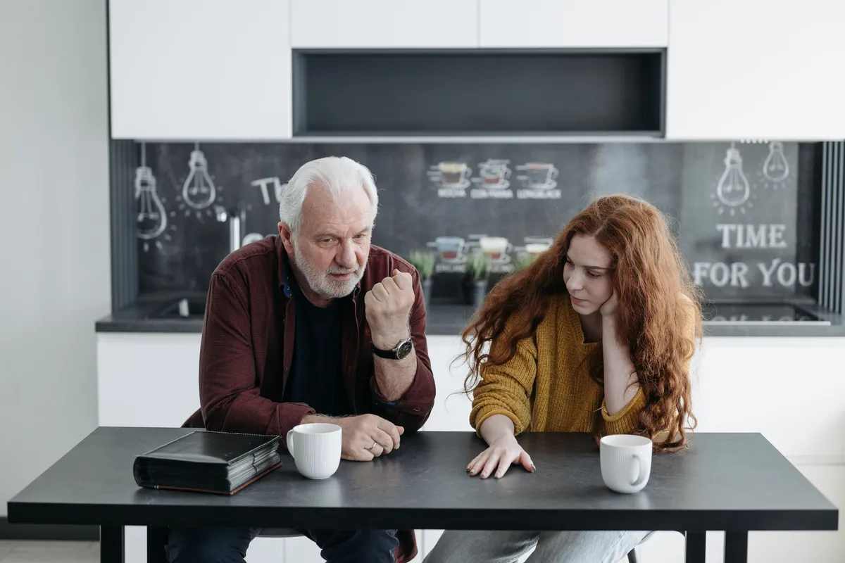 Two people talking across a table, one listening without defending