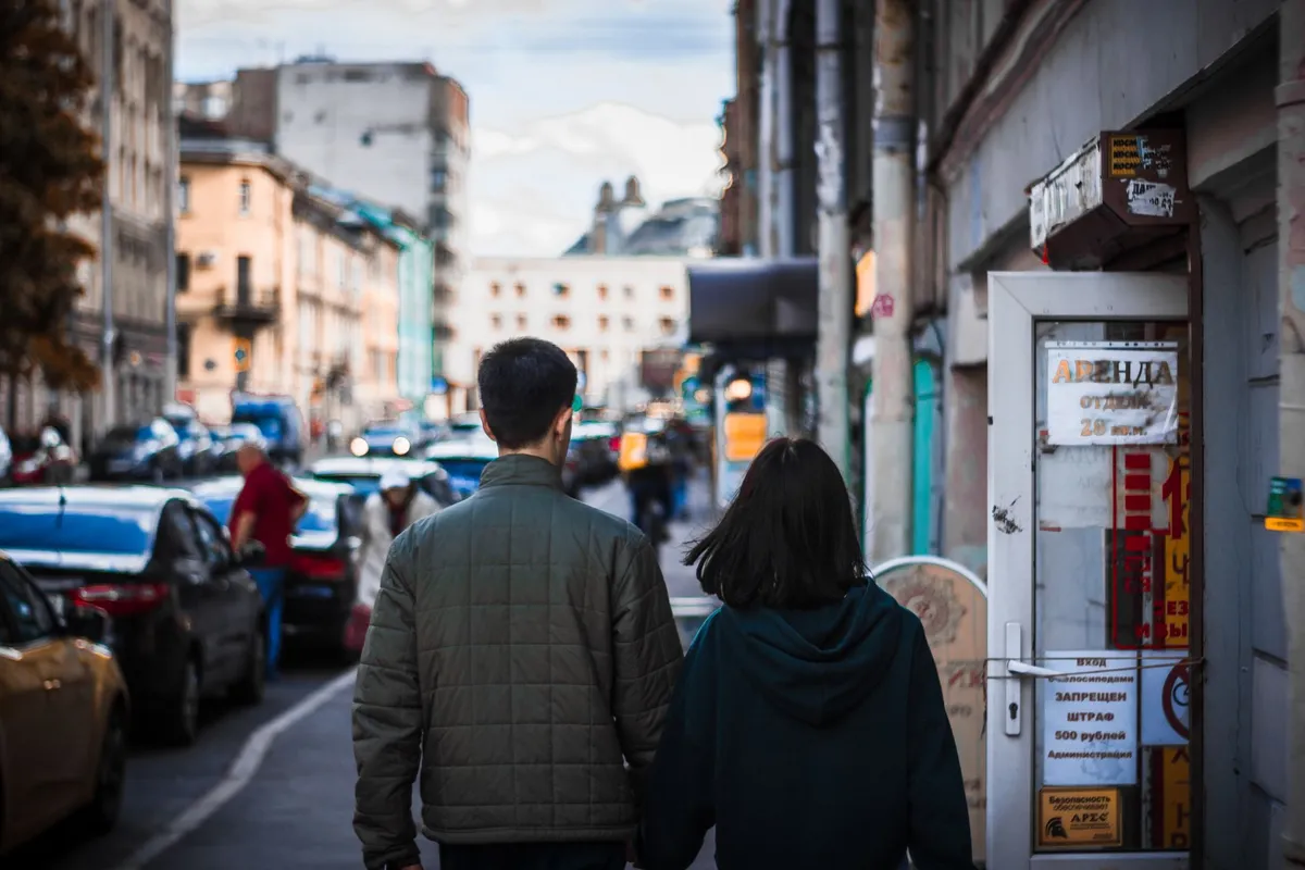 A couple walking side by side down a city street seen from behind