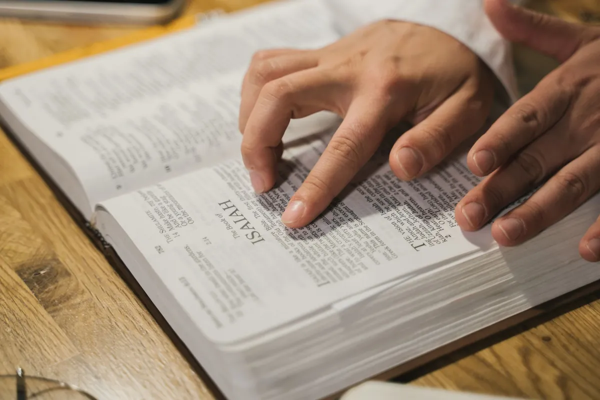A pair of hands resting on the open pages of a Bible