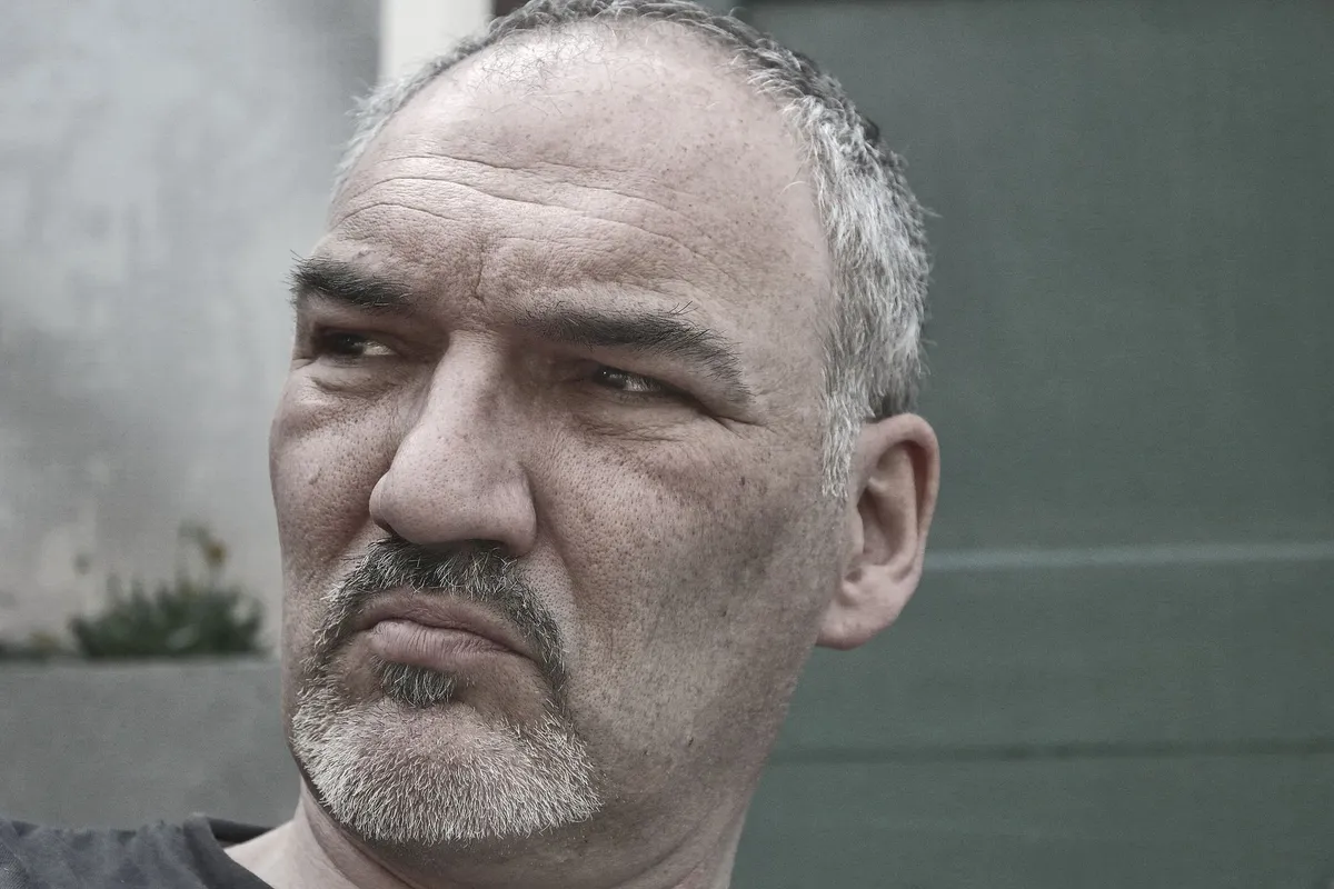 A man in his forties standing outdoors, thinking through whether to see a therapist for a midlife crisis