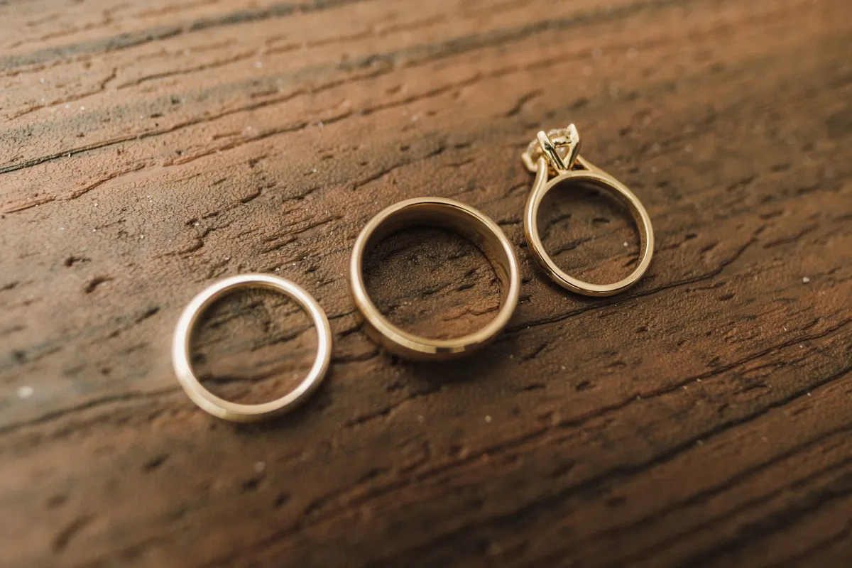 Three gold wedding rings resting on a wooden surface