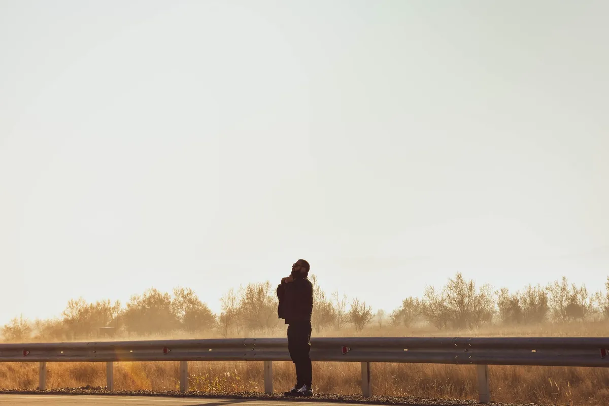 A person standing alone on a quiet road looking ahead