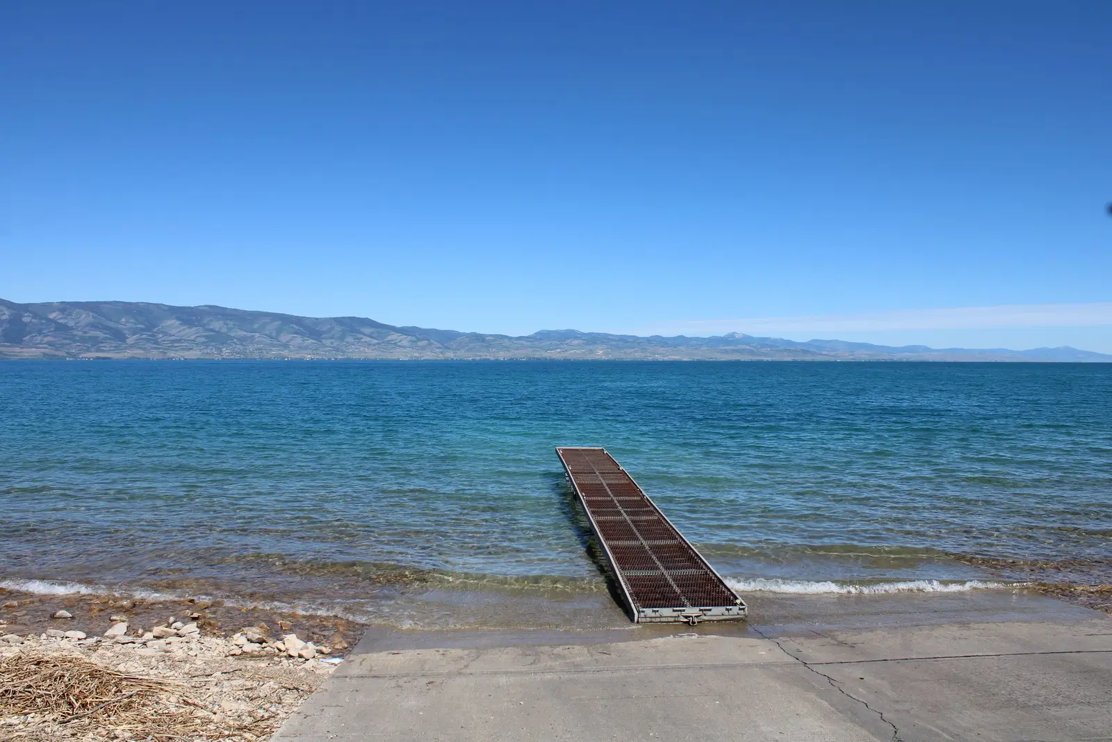 A clear blue mountain lake in Utah with a pier running out from the shore